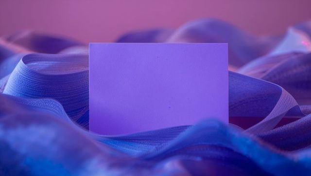Blank card on wavy fabric under purple lighting