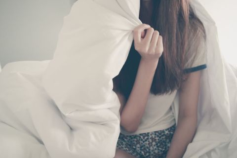 Young Woman Relaxing in Bed with Cozy White Bedding