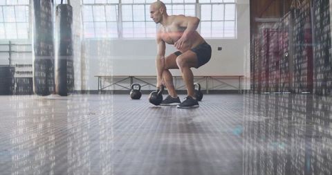 Focused athlete lifting kettlebell in stylish gym