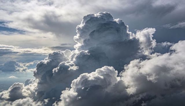Towering cumulonimbus thunderhead rising with sunlit edges and dramatic backlit sky