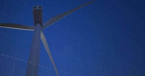 Upward perspective of wind turbine tower with three-blade rotor against deep blue sky