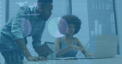 Black woman pointing at laptop, colleague holding tablet collaborating on data analytics