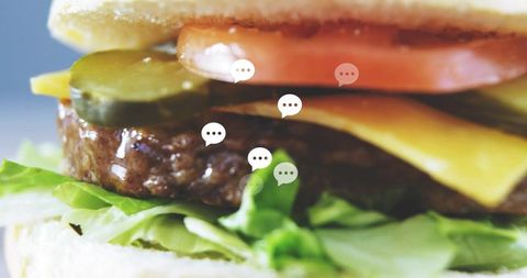 Macro juicy cheeseburger featuring melted cheese, lettuce, tomato, pickles and chat bubbles