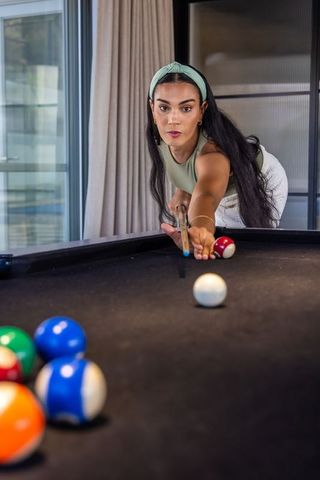 Focused african american woman playing pool in modern home game room