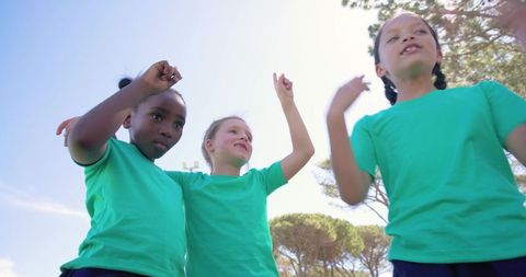 Youth girls celebrating teamwork and friendship outdoors in matching green shirts