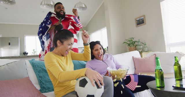 Group of diverse friends enjoying a soccer game at home while celebrating and cheering. Ideal for themes of camaraderie, sports fans, leisure time, and multicultural gatherings. Perfect for advertisements, blog posts, social media, and articles focused on soccer enthusiasts and home entertainment.