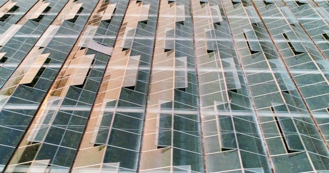 Reflective glass panels on a modern building create a pattern of lines and distorted reflections. The design exemplifies contemporary architectural aesthetics and the use of glass to merge indoor and outdoor spaces.