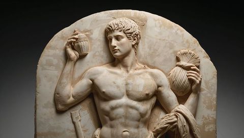 Classical marble relief displaying youthful male holding vessels and drapery