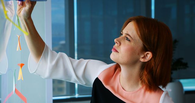 Red-haired Woman Carefully Examining Colorful Mobile in Office Setting - Download Free Stock Images Pikwizard.com