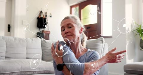 Senior woman stretching shoulder at home with telehealth overlay for mobility and wellness