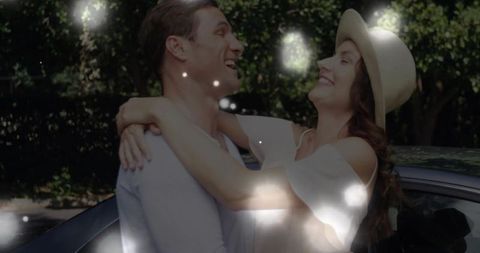 Joyful Couple Embracing Beside Car in Sunlit Driveway