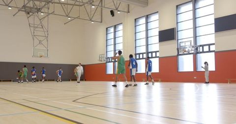 Male Basketball Players Practicing with Coach in Bright Gymnasium