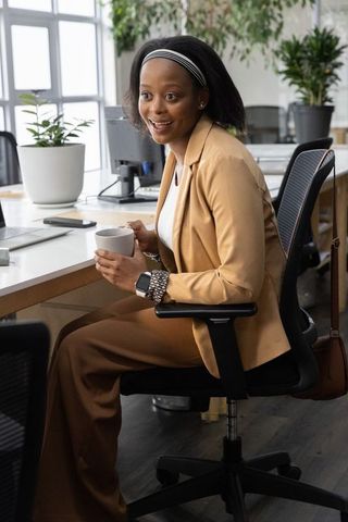 African american professional holding steaming ceramic mug at modern bright office workstation
