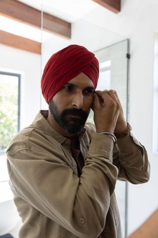 Man in Red Turban Adjusting Earring in Modern Bathroom