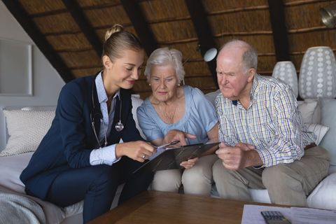 Female Doctor Consults Senior Couple at Home on Healthcare Advice