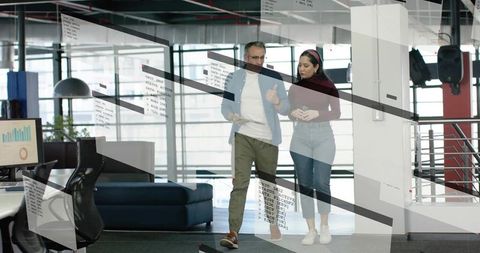 Walking colleagues discussing analytics and code in modern glass-walled open office