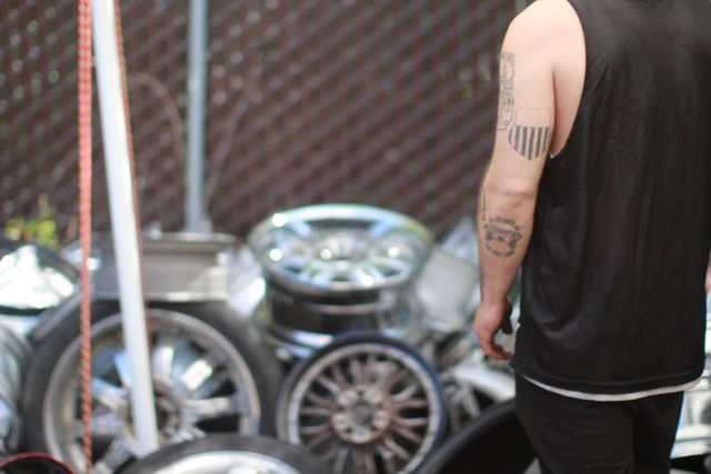 Man with Tattoo Inspecting Stacked Automotive Wheels in Garage - Download Free Stock Photos Pikwizard.com
