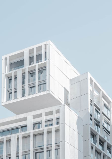 Modern white building with cubic design against clear sky, showcasing minimalist architecture. Perfect for illustrating concepts of contemporary urban structures, real estate, and architectural design.