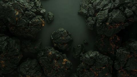 Glowing volcanic boulders surrounding smooth dark pool with orange lava veins