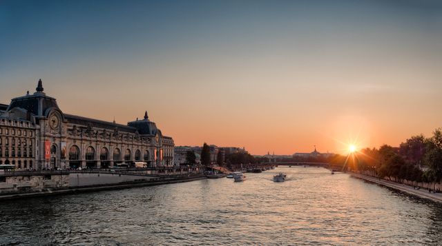 Sunset over Seine River with historic building and boats cruising on water in Paris. Perfect for travel blogs, tourism promotions, or cityscape highlights. Suitable for marketing materials focusing on romantic getaways, cultural experiences, or evening city views.