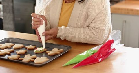 Senior woman decorating christmas cookies at home
