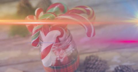Rustic candy cane jar with pine cones and plaid ribbon, festive cozy holiday still life