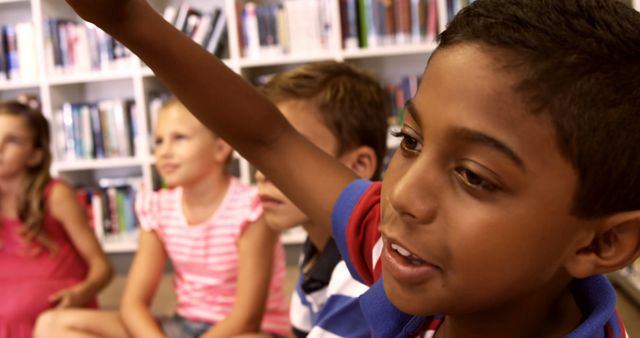 Young boy raising hand in classroom with friends - Download Free Stock Images Pikwizard.com