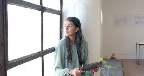 Professional Woman Contemplating Ideas in Modern Office with Tablet