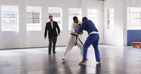 Martial artists grappling in dojo with instructor
