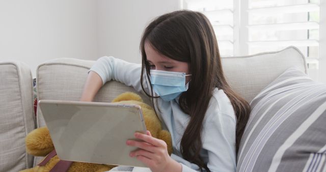 Young Girl in Mask Using Tablet on Couch - Download Free Stock Images Pikwizard.com