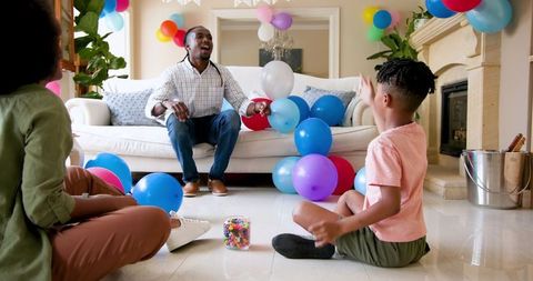 Family Celebrating Boy's Birthday with Joyful Ball Tossing at Home