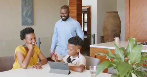 African american parents supporting son using tablet for homework in modern open-plan kitchen