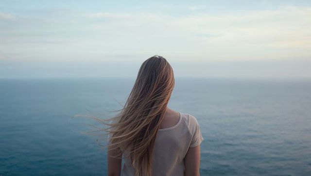 Solitary Woman Contemplating Sea from Coastal Cliff