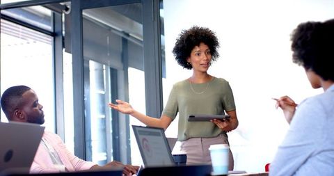 Confident Young Professional Leading Office Meeting with Team
