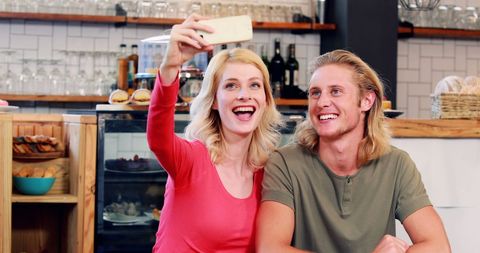 Smiling Young Couple Taking Selfie in Urban Cafe Setting