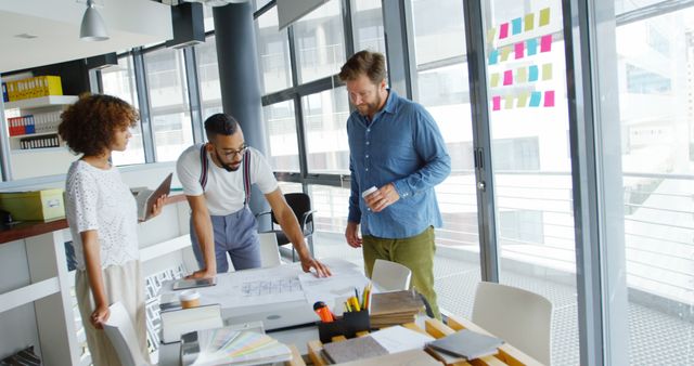 Business team reviewing blueprints in modern office building - Download Free Stock Images Pikwizard.com