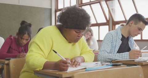 Diverse high school students focusing diligently in classroom