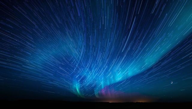 Aurora Borealis and Star Trails Sweeping Night Sky with Crescent Moon and Horizon Glow