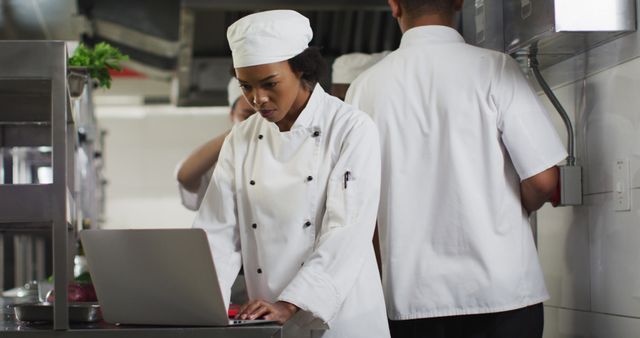 African american female chef using laptop in restaurant kitchen - Download Free Stock Photos Pikwizard.com