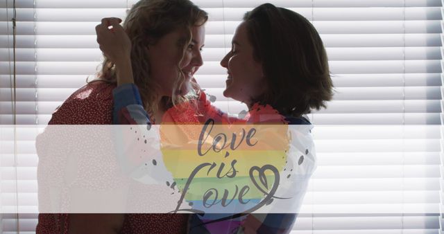 Image of rainbow heart and love is love over lesbian couple embracing at home. lgbt rights and equality concept digitally generated image.