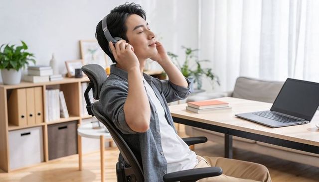 Young professional relaxing with headphones in minimalist home workspace during break