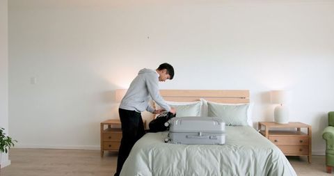 Couple Packing Suitcase Preparing for Travel Adventure in Bedroom