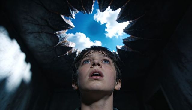 Teenage boy gazing through serrated roof hole toward blue sky dramatic ruin interior