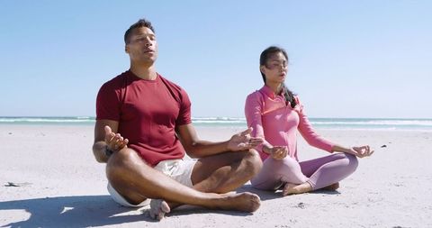 Diverse Couple Meditating Cross-Legged on Sandy Beach, Mindfulness by Sea