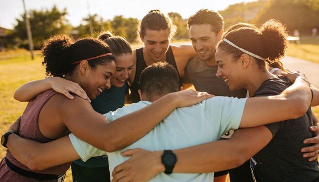 Diverse team huddling in park at golden hour showing camaraderie and motivation