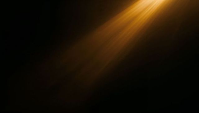 Casting warm golden diagonal light beam across dark space with hazy cinematic glow