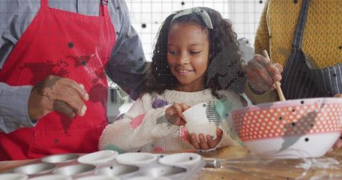 Smiling Child Preparing Muffin Liners while Baking with Multigenerational Family