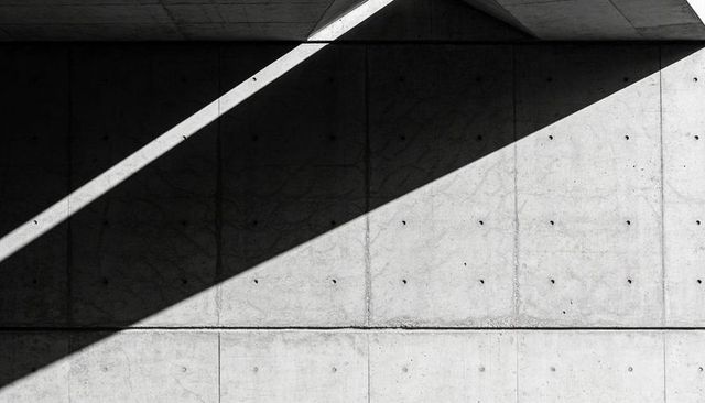 Diagonal Shadow Crossing Brutalist Concrete Wall With Circular Tie Holes and Seam
