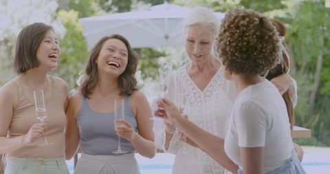 Women Laughing and Enjoying Drinks at Outdoor Celebration