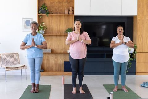 African american women practicing yoga at home senior friends meditating in living room